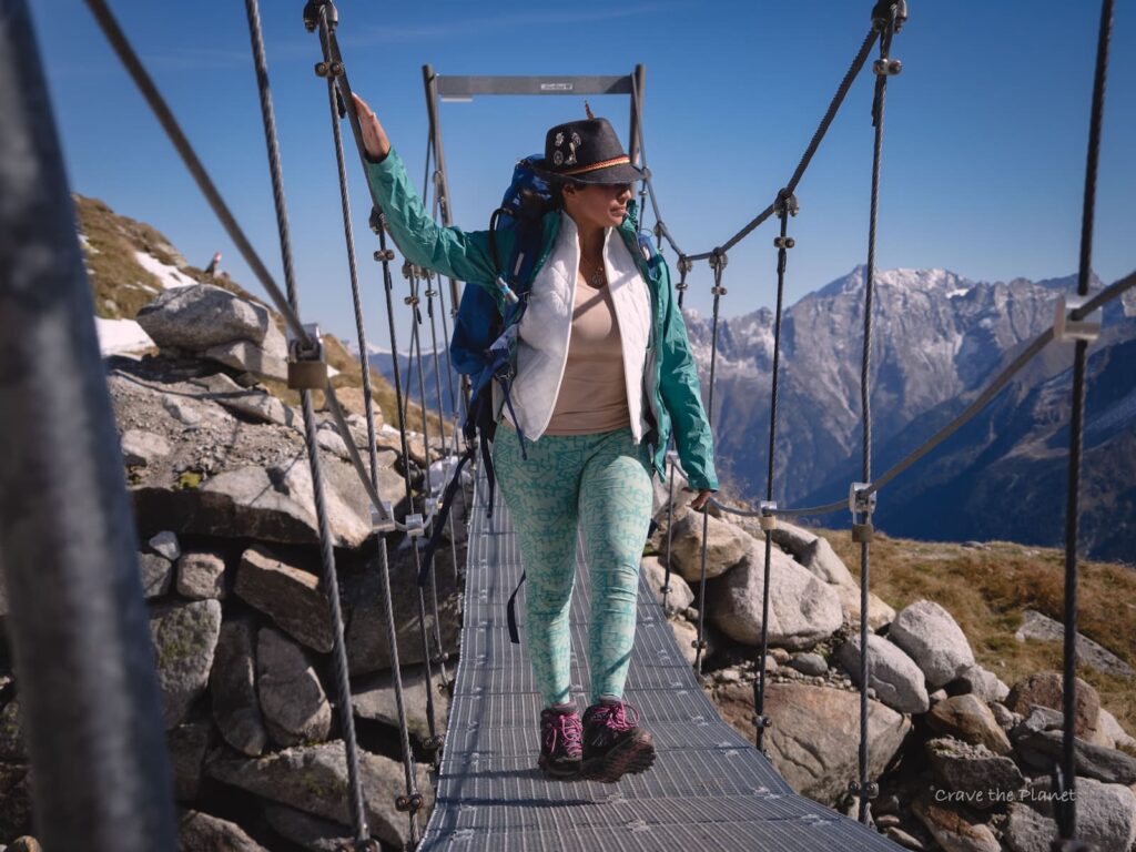 woman in a hiking jacket crossing the olpererhutte bridge