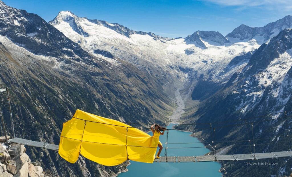woman in flying dress in austria at olpererhutte bridge