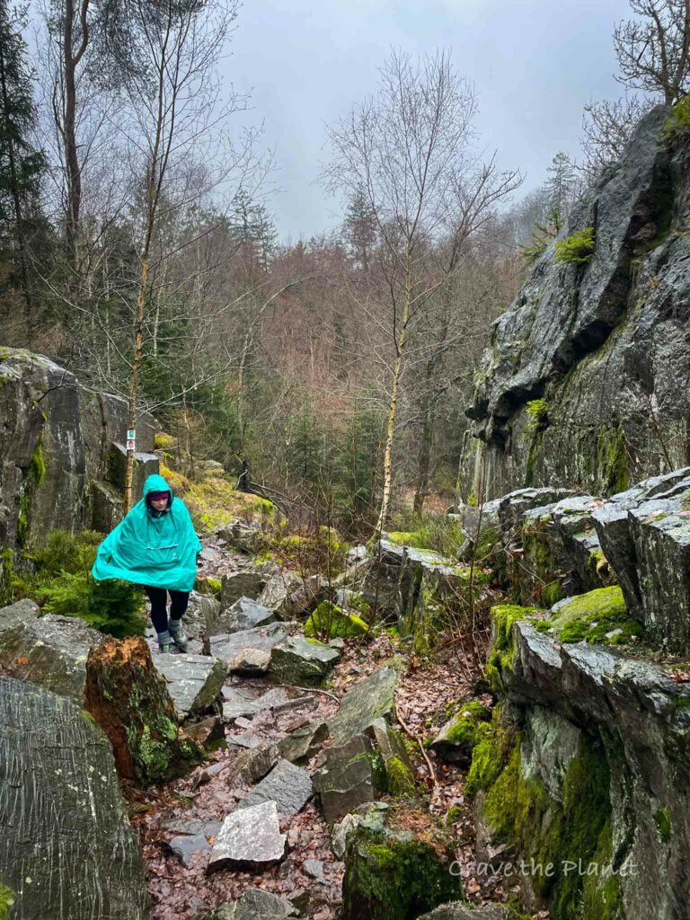 woman in blue rain poncho hiking the barenfelsen in germany